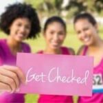 Three women in casual athletic attire hold a pink "Get Checked" card, promoting Breast Cancer Awareness for B&L Plumbing.
