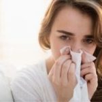 Young woman indoors with a tissue, showing vulnerability while exploring water filtration options from B&L Plumbing.