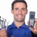 Male technician in blue uniform holding wrenches and a mobile phone for plumbing at B&L Plumbing in Colorado Springs.