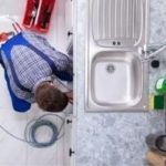 Person repairing a kitchen sink with tools and supplies for home plumbing maintenance at B&L Plumbing.