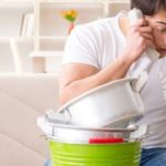 Man on phone amid kitchen items, highlighting B&L Plumbing's tips for preventing plumbing emergencies in Colorado Springs.