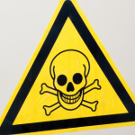 Warning sign with skull and crossbones, set against a yellow triangle, symbolizes danger related to plumbing hazards.
