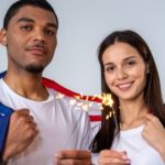 Man draped in a flag and woman with a sparkler, celebrating with B&L Plumbing logo in the background.
