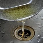 Oil pouring from a pan into a sink drain, highlighting proper grease disposal tips from B&L Plumbing.