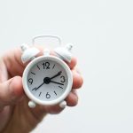 A small white alarm clock held in a hand, symbolizing B&L Plumbing's timely and efficient service in Colorado Springs.