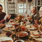 Five adults celebrating a festive dinner with a dog, illustrating B&L Plumbing's holiday preparedness tips.