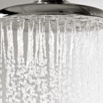 Showerhead with water flowing, showcasing a sleek silver finish for modern bathroom upgrades by B&L Plumbing.