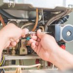 Technician repairing a heating system with tools, showcasing HVAC maintenance by B&L Plumbing.
