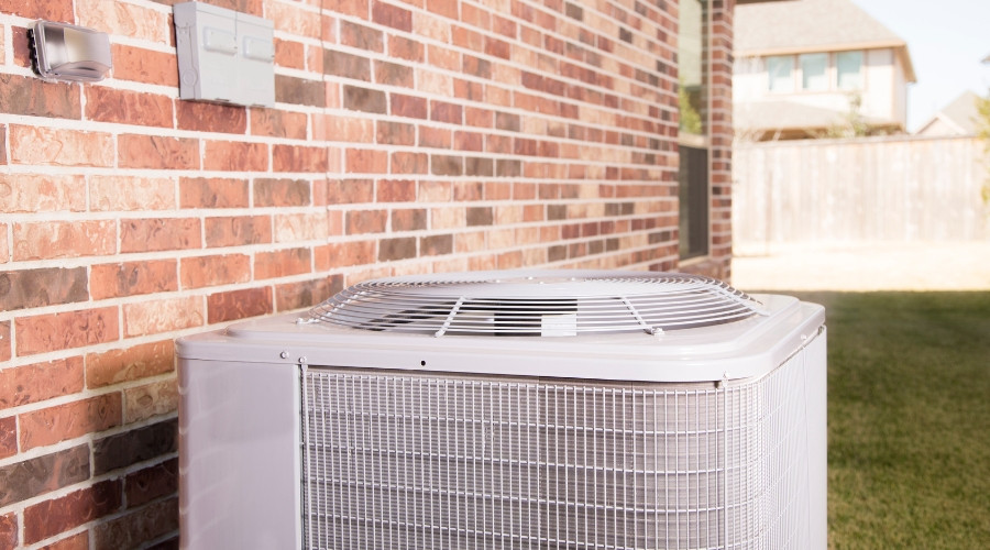 Air conditioning unit installed outside a brick wall, illustrating central air conditioning system components relevant to HVAC maintenance and efficiency.