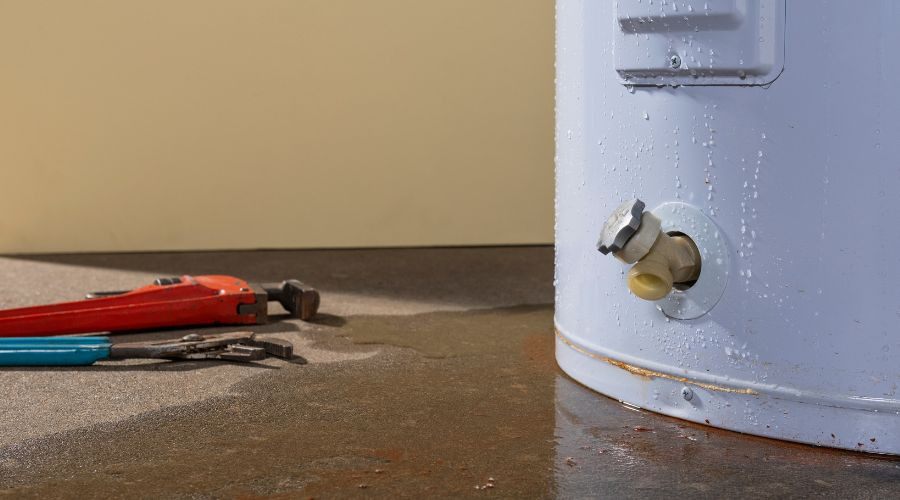 Water heater with visible valve and plumbing tools, indicating maintenance or replacement needs in plumbing services.